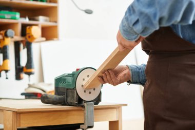 Genç ve yetenekli bir kadın ahşap işçiliği yapıyor, odun parçasını odaklama ve tutku ile şekillendiriyor..