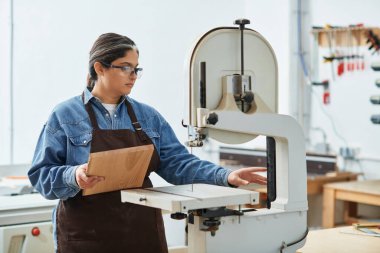 Tutkulu genç kadın, canlı bir atölye ortamında ahşap projesine odaklanıyor..