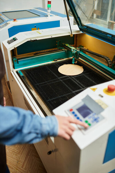 A beautiful young woman interacts with a laser cutting machine, showcasing her skills at a workshop.