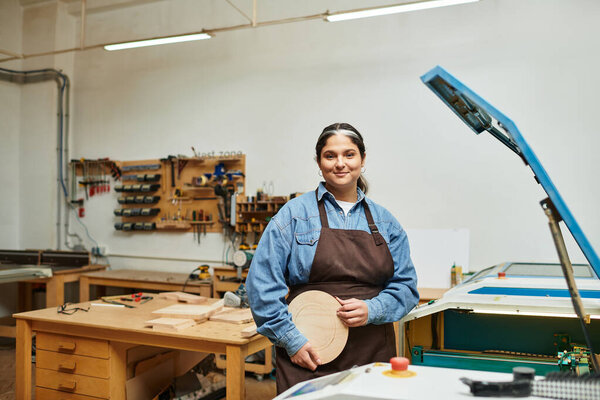 A talented young woman stands confidently in a workshop, showcasing her craftsmanship with pride.