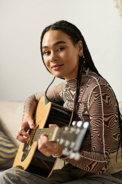 Modern bir dairede, genç bir Afrikalı Amerikalı kadın gitar çalmaktan zevk alıyor, tutkusunu ifade ediyor..