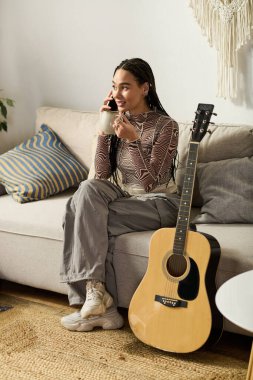 Parlak ve neşeli genç bir kadın şık kıyafetler içinde evde dinlenirken telefonda sohbet ediyor..