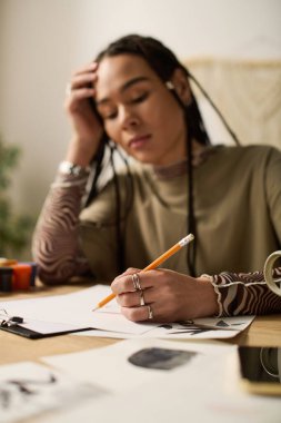 Şık dairesinde, örgülü genç bir kadın tutkulu bir şekilde kağıda çizimler yapıyor, düşüncelere dalmış..