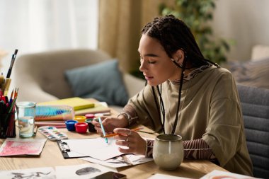 Örgülü odaklanmış genç bir kadın sanatsal yönünü modern ve şık bir evde keşfediyor..