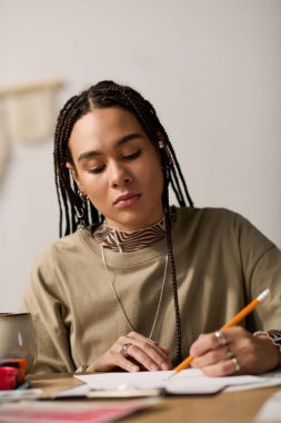 Saçları örgülü genç siyahi bir kadın gün boyunca şık dairesinde yaratıcı bir şekilde resim çiziyor..