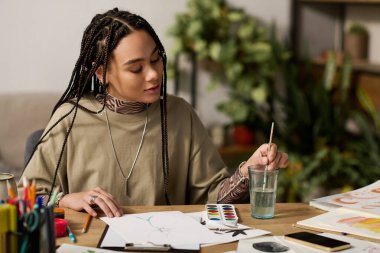 Örgülü genç bir Afrikalı Amerikalı kadın modern ve şık dairesinde resim yapmaktan hoşlanıyor..