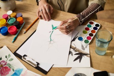 Genç bir kadın, rahat dairesinde sanatsal malzemelerle çevrili bir şekilde resim yapıyor..