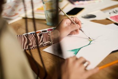 Örgülü genç bir kadın şık evinde resim yaparken yaratıcılığını ifade eder..