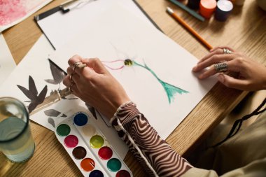 Örgülü genç bir kadın şık dairesinde canlı bir şekilde resim yapıyor, yaratıcılığı kucaklıyor..