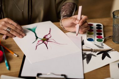 Genç bir kadın, sanatla çevrili şık evinde suluboya resim yapıyor..