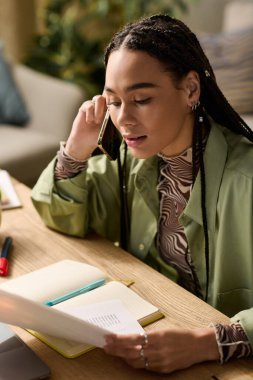 Çekici Afrikalı Amerikalı kadın şık giyinmiş modern çalışma alanında telefonla konuşuyor..