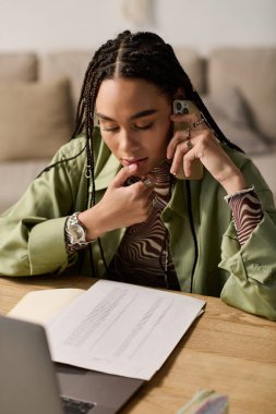 Örgülü genç bir Afrikalı Amerikalı kadın modern dairesinde işine odaklanıyor..