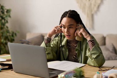 Saçları örgülü genç bir Afrikalı Amerikalı kadın masasında oturuyor ve görevleriyle çok meşgul..