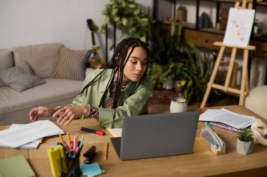 Saçları örgülü genç bir zenci kadın şık dairesinde masasında dinleniyor..