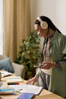 Saçları örgülü genç bir Afrikalı Amerikalı kadın çağdaş yaşam alanında notlar almaktan hoşlanıyor..