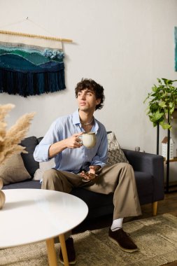 Genç adam kanepede rahatlar, kahvesini yudumlar ve şık dairesini takdir eder..