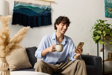 Kıvırcık saçlı yakışıklı genç adam şık dairesinde rahatlıyor, kahvesini yudumluyor ve gülümsüyor..