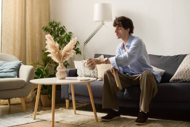 Genç bir adam modern dairesinde rahat bir şekilde oturur ve huzurlu bir anın tadını çıkarır..