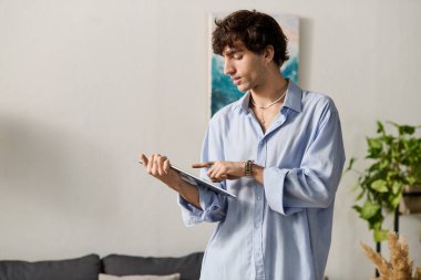 Mavi gömlekli kıvırcık saçlı genç adam, içeride yaratıcı bir işe girişiyor..