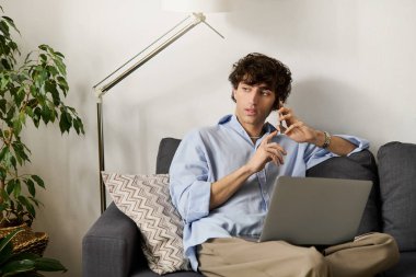 Yakışıklı genç adam, modern bir dairede rahat bir şekilde oturur ve bir telefon görüşmesi yapar..