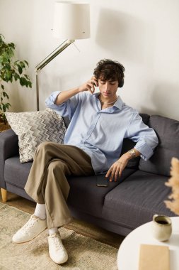 Şık bir genç adam modern dairesinde rahatça oturur ve müzik dinler.