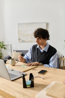 Mavi gömlekli genç adam güzel, parlak dairesinde notlar yazmaya odaklanıyor..