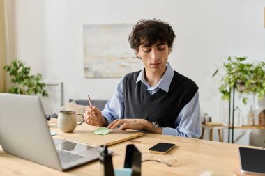 Kıvırcık saçlı şık bir genç adam bitkilerle dolu parlak ve modern dairesinde notlar yazıyor..