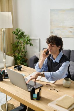 Modern masasında çalışırken telefonda konuşan kıvırcık saçlı genç bir adam..