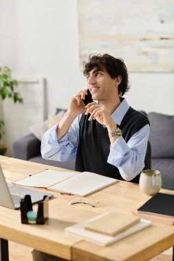 Kıvırcık saçlı yakışıklı genç adam şık bir apartman dairesinde telefonla konuşuyor..
