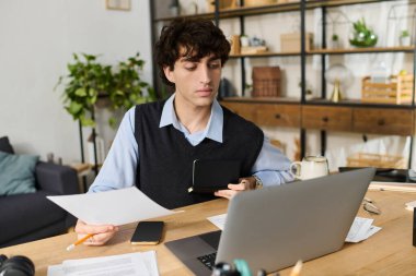 Yakışıklı mavi gömlekli genç, şık masasında otururken belgeleri inceliyor..