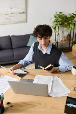 Mavi gömlekli yakışıklı genç adam evinde rahat ve şık bir yerde notlarla meşgul oluyor..