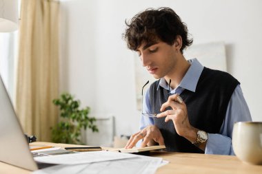 Mavi gömlekli genç adam güneş ışığıyla dolu şık bir dairede görevlerine odaklanıyor..