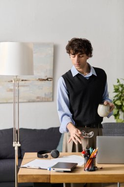 Mavi gömlekli kıvırcık saçlı genç adam modern dairesinde sakin bir öğleden sonranın tadını çıkarıyor..