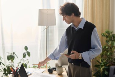 Modern mavi tişörtlü yakışıklı genç bir adam çalışma alanını düzenliyor. Şık bir dairede..