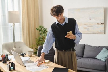 Genç adam rahat bir yerde cep telefonu cihazına odaklanırken akıllı bir şekilde evrak düzenliyor..