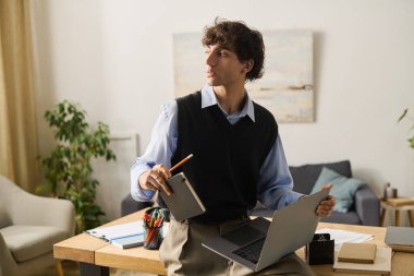 Genç adam, modern yaşam tarzını sergileyerek şık dairesinde iş ve yaratıcılığı birleştiriyor..