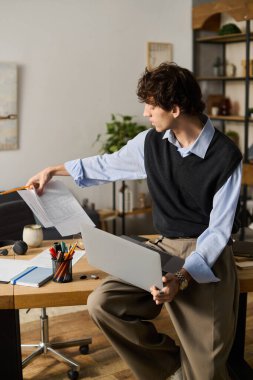 Kıvırcık saçlı genç adam, şık çalışma alanındaki belgeleri analiz ediyor..