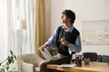 Kıvırcık saçlı yakışıklı genç adam şık dairesinde otururken fikir üretiyor..