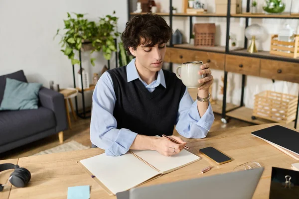 Kıvırcık saçlı genç, rahat bir dairede bir masada oturuyor, kahvesini yudumluyor ve fikirlerini düşünüyor..
