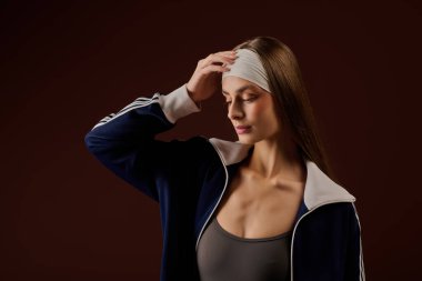 Formda genç sporcu kadın stilini ve gücünü minimalist kahverengi bir stüdyoda sergiliyor..