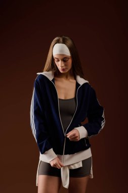 Modayı takip eden atletik giysili genç bir kadın sıcak bir stüdyoda rahatça poz veriyor..