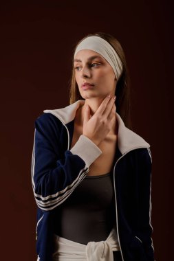 Formda genç bir kadın atletik tarzını moda, sıcak tonlu bir ortamda sergiliyor..