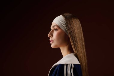 Giyim kuşamında formda genç bir kadın şık bir saç bandıyla kendine güvenerek poz veriyor..