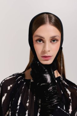 Güzel, genç bir kadın zarif elbisesini en az gri stüdyo ortamında sergiliyor..