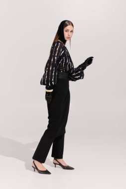 Güzel genç bir kadın zarif moda anlayışını çağdaş bir stüdyoda sergiliyor..