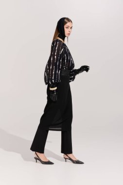 Modern bir stüdyoda zarif genç bir kadın zarif kıyafetlerini sergiliyor..