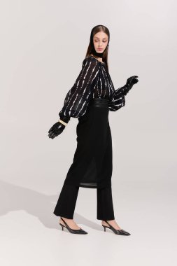 Güzel genç bir kadın, gri bir stüdyo arkaplanına kafa bandıyla şık bir moda sergiliyor..