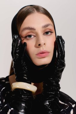 Zarif genç bir kadın zarif gri bir stüdyoda zarif bir şekilde poz veriyor, zarif kıyafetinin altını çiziyor..