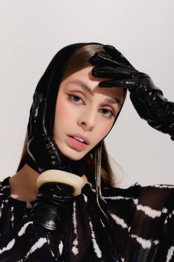 Şık giyinmiş zarif genç bir kadın zarif gri bir stüdyoda zarif pozlar veriyor..