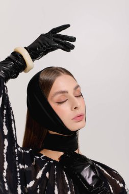 Zarif giyinmiş güzel bir genç kadın zarif bir şekilde gri arkaplanlı modern bir stüdyoda poz veriyor..